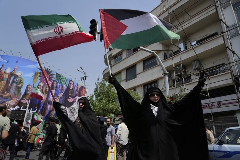 Manifestantes iraníes ondean banderas de Irán y Palestina en una concentración contra Israel en Teherán, Irán, el 13 de junio de 2025. (AP Foto/Vahid Salemi)