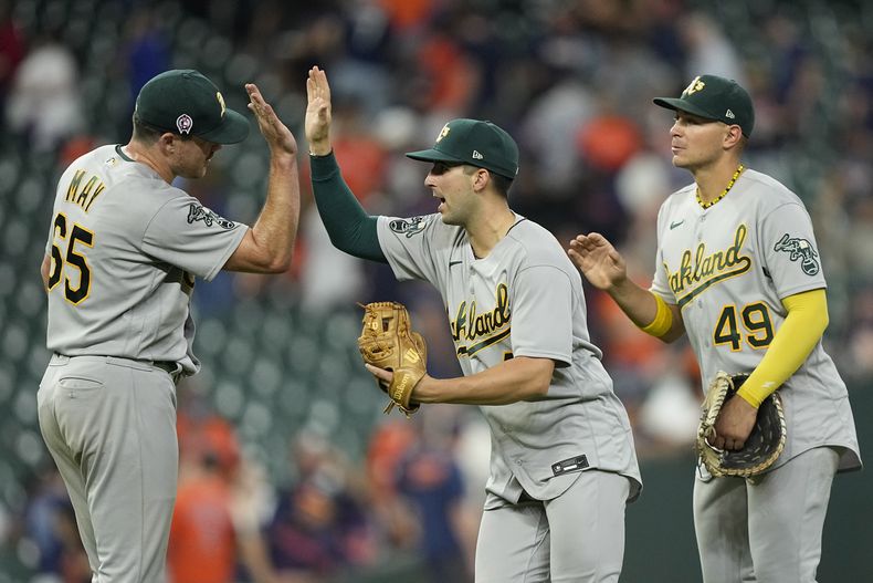 Trevor May (65), Kevin Smith, centro, y Ryan Noda (49), de los Atléticos de Oakland, celebran después de derrotar a los Astros de Houston, el lunes 11 de septiembre de 2023, en Houston. Los Atléticos ganaron 4-0. (AP Foto/David J. Phillip)