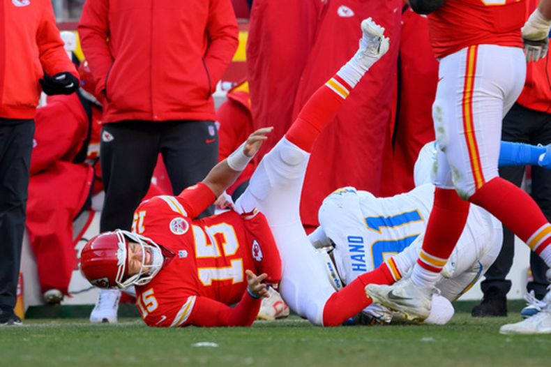 ARCHIVO - Patrick Mahomes (15), quarterback de los Chiefs de Kansas City, resulta lesionado al ser derribado por DaShawn Hand (91), tackle defensivo de los Chargers de Los Ángeles durante la segunda mitad del partido de la NFL el 14 de diciembre de 2025, en Kansas City, Misouri. (AP Foto/Reed Hoffmann, Archivo)
