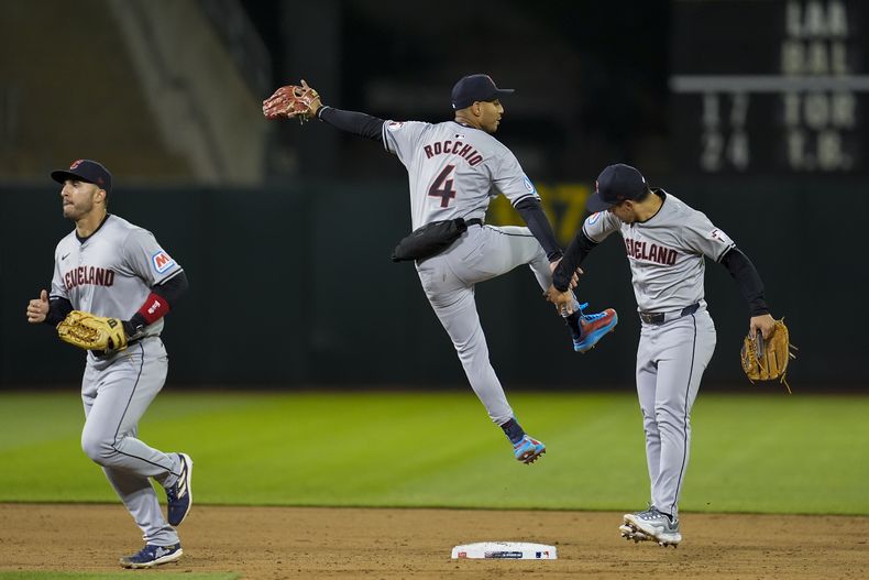 Brayan Rocchio (centro), intercambia una palmada con Steven Kwan, su compañero de los Guardianes de Cleveland, tras el triunfo sobre los Atléticos de Oakland, el jueves 28 de marzo de 2024 (AP Foto/Godofredo A. Vásquez)