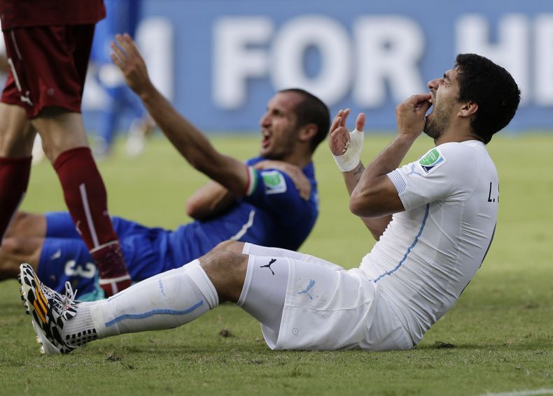 El uruguayo Luis Su&aacute;rez se lleva una mano a los dientes luego de dar una aparente mordida a Giorgio Chiellini, de Italia, durante el partido del Grupo D mundialista, el martes 24 de junio de 2014, en Natal, Brasil (AP Foto/Ricardo Mazal&aacute;n)