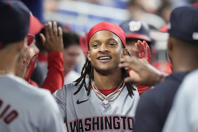 CJ Abrams de los Nacionales de Washington felicitado por sus compañeros tras anotar en un sencillo del mexicano Joey Meneses en la octava entrada del juego ante Marlins de Miami el viernes 26 de abril del 2024. (AP Foto/Wilfredo Lee)