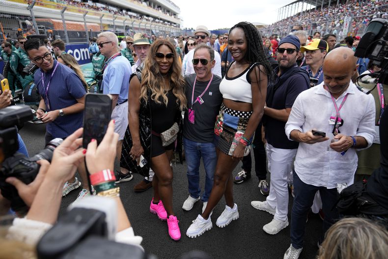 Serena Williams, Venus Williams posan con un aficionado de la F1 en la parrilla de salida antes del inicio del Gran Premio de Miami el domingo 7 de mayo dle 2023. (AP Foto/Rebecca Blackwell)