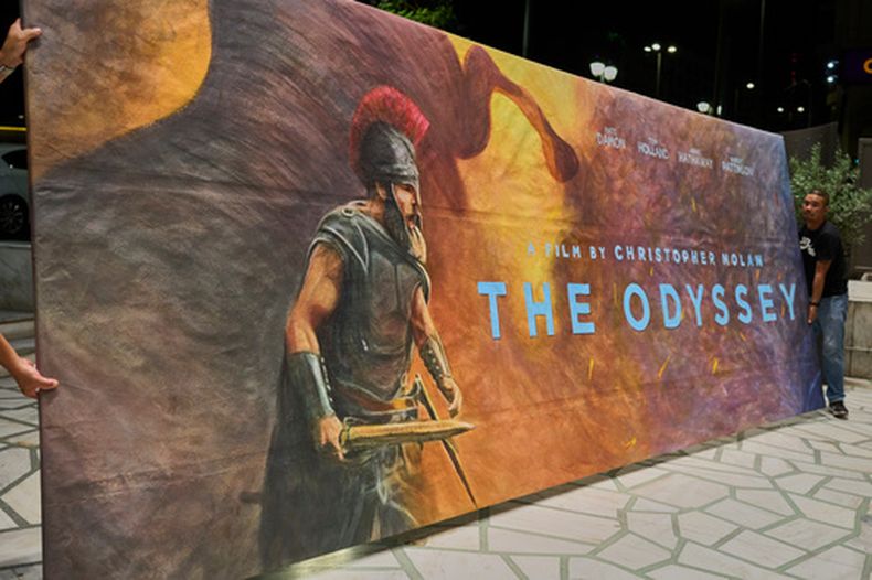 Trabajadores instalan un cartel pintado a mano, obra de la artista Virginia Axioti, para la próxima película de Christopher Nolan, The Odyssey, protagonizada por Matt Damon en el papel de Odiseo, frente al cine Athinaion de Atenas, el sábado 11 de julio de 2026. (Foto AP/Petros Giannakouris)