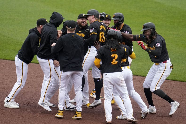 Jack Suwinski (65), de los Piratas de Pittsburgh, celebra con sus compañeros de equipo después de impulsar la carrera de la victoria con un sencillo ante el relevista de los Rockies de Colorado, Nick Mears, durante la novena entrada de un juego de béisbol en Pittsburgh, el sábado 4 de mayo de 2024. (AP Foto/Gene J. Puskar)