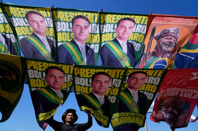Un vendedor ambulante vende banderas de campaña de los principales candidatos presidenciales de Brasil: el senador Flavio Bolsonaro y el actual presidente Luiz Inácio Lula da Silva, en Brasilia, Brasil, el martes 29 de septiembre de 2026. (AP Foto/Eraldo Peres)