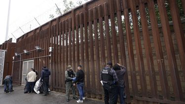 Oficiales federales estadounidenses le quitan las esposas a hombres antes de liberarlos cerca de la muralla fronteriza en San Diego el 15 de marzo de 2023. (Foto AP /Gregory Bull)