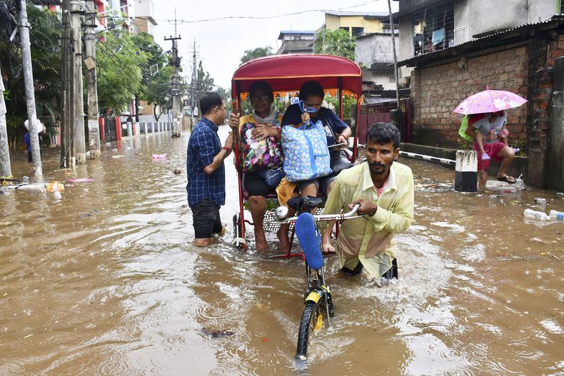 Residentes cruzan una calle inundada en un bicitaxi luego de unas fuertes lluvias en Guwahati, India, el sábado 31 de mayo de 2025. (AP Foto)