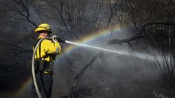 Un bombero rocía con agua parte de la zona arrasada por el incendio Archer, en Granada Hills, Los Ángeles, el 10 de enero de 2025. (AP Foto/Ethan Swope)