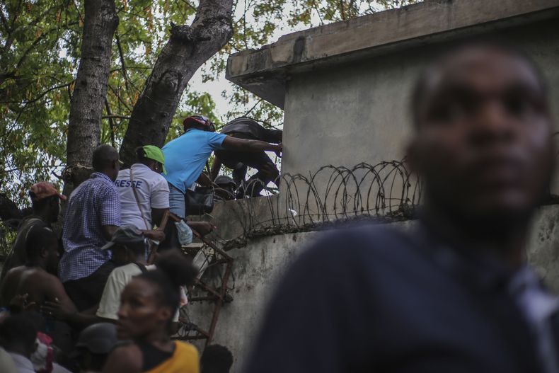 Periodistas se encaraman sobre una pared para evitar disparos de una pandilla en el Hospital General en Puerto Príncipe, el 24 de diciembre del 2024. (AP foto/Jean Feguens Regala)