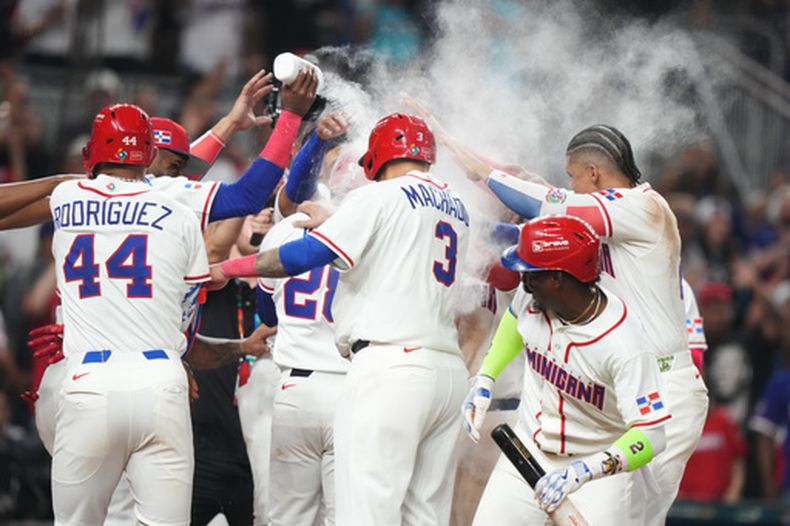 Austin Wells (28), centro, de República Dominicana, recibe un baño de parte de sus compañeros después de batear cuadrangular de tres carreras para dejar en el terreno a Corea del Sur en la séptima entrada del juego de béisbol del Clásico Mundial el viernes 13 de marzo de 2026, en Miami. (AP Foto/Lynne Sladky)