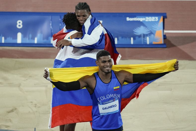 El colombiano Arnovis Dalmero (al frente) celebra tras ganar el salto largo del atletismo de los Juegos Panamericanos en Santiago, Chile, el martes 31 de octubre de 2023. Atrás los cubanos Alejandro Parada y Maikel Vidal. (AP Foto/Fernando Vergara)