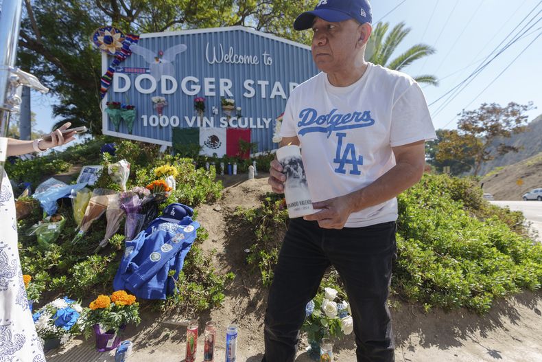 Rafael Gómez, inmigrante salvadoreño, enciende una vela en un altar improvisado afuera del Dodger Stadium en memoria del exlanzador mexicano Fernando Valenzuela, el miércoles 23 de octubre de 2024 (AP Foto/Damian Dovarganes)