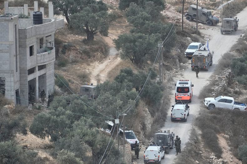 Soldados israelíes aseguran un edificio en construcción mientras varias ambulancias evacúan a palestinos heridos tras un ataque perpetrado por colonos israelíes en el poblado de Qusra, en Cisjordania, el sábado 29 de agosto de 2026. (AP Foto/Majdi Mohammed)