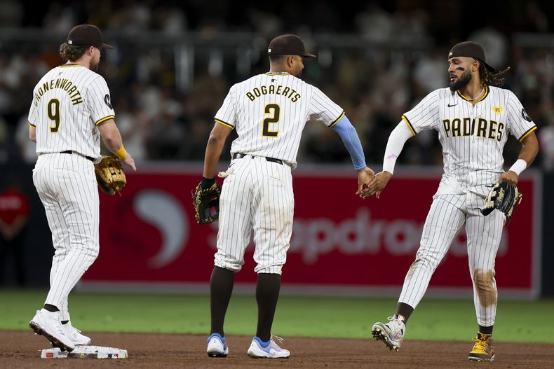 De izquierda a derecha, el segunda base de los Padres de San Diego, Jake Cronenworth, el campocorto Xander Bogaerts y el jardinero derecho Fernando Tatis Jr. celebran después de su victoria contra los Medias Blancas de Chicago, el sábado 21 de septiembre de 2024, en San Diego. (AP Foto/Ryan Sun)