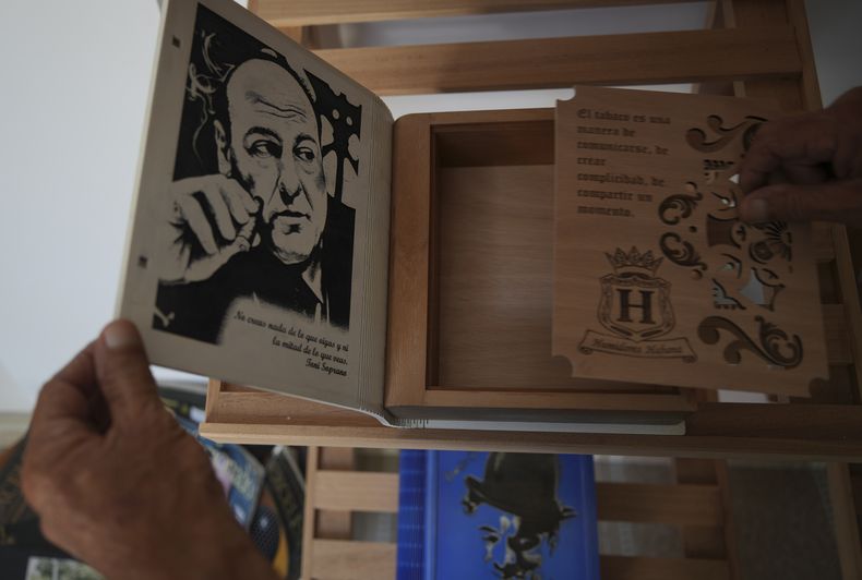 Un artesano que trabaja en el Taller de Creación de Arte Humidores Habana muestra un humidificador de cigarros decorado con los Soprano en La Habana, Cuba, el miércoles 19 de febrero de 2025. (AP Foto/Ramón Espinosa)