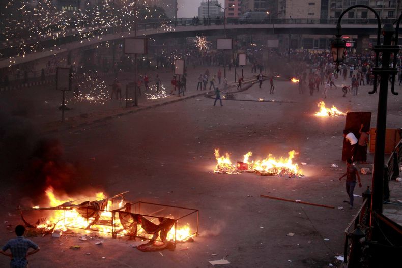 Multitudes partidarias a la milicia y al ex presidente egipcio Mohammed MOrsi lanzan piedras y prenden fuegos en una manifestaci&oacute;n el domingo, 6 de octubre de 2013, en El Cairo. (AP Photo/Emad Abdul Rahman)