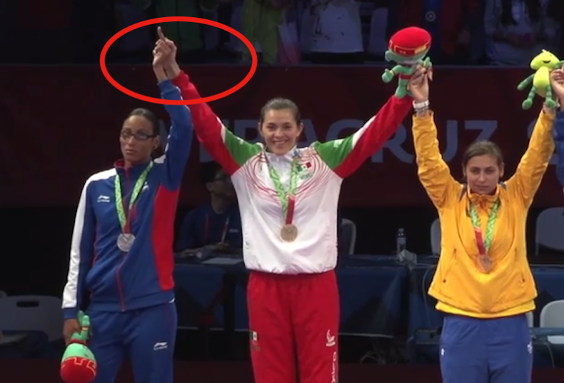 Inconforme, la cubana y Campeona del Mundo en la División de -73 kg, Glenhis Hernández, levantó el dedo medio en señal de protesta en el podio de la premiación de la categoría en el taekwondo de los JCC Veracruz 2014.
