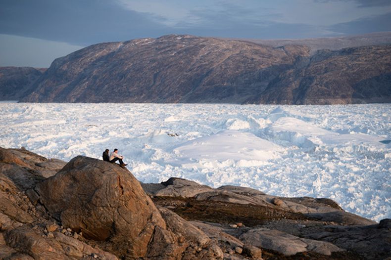 ARCHIVO - Estudiantes investigadores de NYU se ven sentados en una roca con vistas al glaciar de Helheim en Groenlandia, el 16 de agosto de 2019. (AP Foto/Felipe Dana, Archivo)