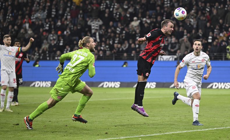 Mario Götze del Eintracht Frankfurt (centro) , anota el primer gol, mientrs que Dominik Kohr (derecha), y el portero Robin Zentnerduring, del Mainz, fallan en evitarlo durante el partido de la Liga Alemana entre el Eintracht Frankfurt y el 1. FSV Mainz 05, en el estadio Deutsche Bank Park, el viernes 26 de enero de 2024. (Arne Dedert/dpa via AP)