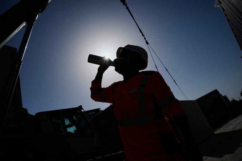 Una persona toma agua mientras trabaja en una construcción bajo un intenso calor, el 24 de junio de 2026, en Boulogne Billancourt, a las afueras de París. (AP Foto/Christophe Ena)