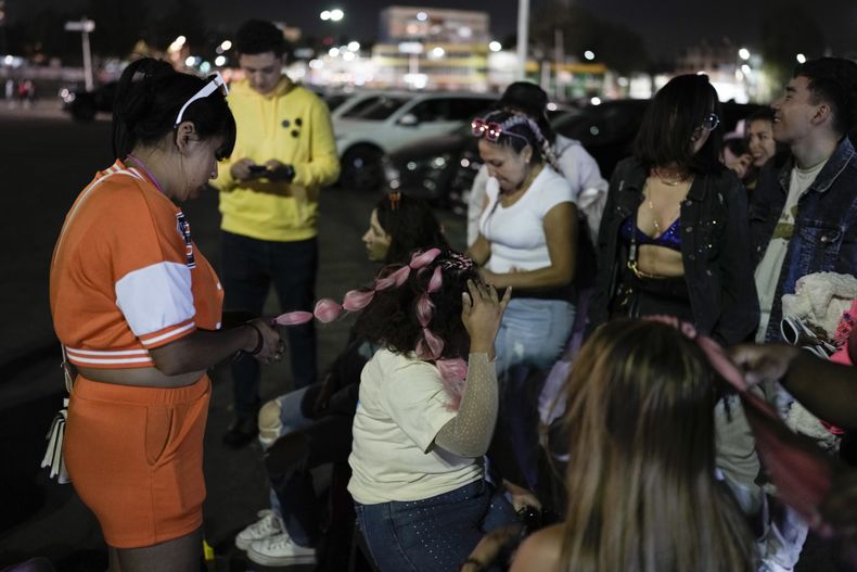 Una mujer se coloca extensiones de cabello rosadas previo al concierto de la gira Mañana será bonito de Karol G en el Estadio Azteca de la Ciudad de México el jueves 8 de febrero de 2024. (Foto AP/Eduardo Verdugo)