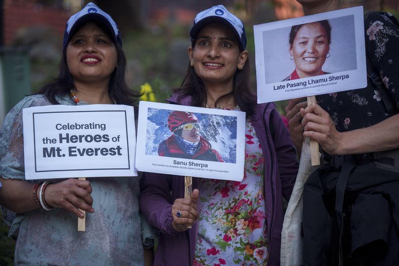 Tres mujeres sostienen carteles y fotos en homenaje a montañeros con récords, en los actos por el 70mo aniversario del primer ascenso a la cima del Everest en Katmandú, Nepal, el lunes 29 de mayo de 2023. (AP Foto/Niranjan Shrestha)