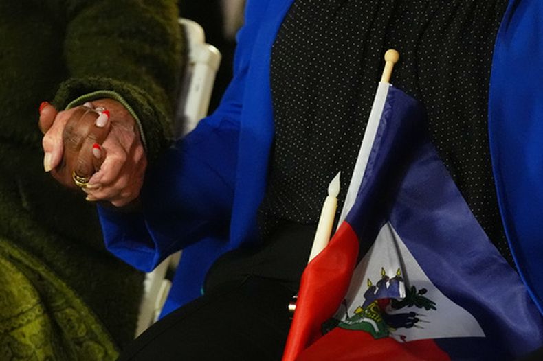 ARCHIVO – Varias personas se toman de las manos y sostienen una bandera de Haití en una vigilia en el complejo cultural Little Haiti después de que un juez federal impidiera que el gobierno del presidente Donald Trump pusiera fin al Estatus de Protección Temporal (TPS, por sus siglas en inglés) para los haitianos, el 3 de febrero de 2026, en el norte de Miami. (AP Foto/Lynne Sladky, Archivo)