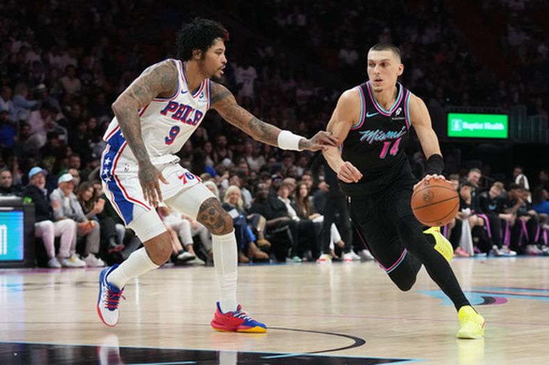 Tyler Herro (14), del Heat de Miami, lleva el balón frente a Kelly Oubre Jr. (9), de los 76ers de Filadelfia, durante la segunda mitad del juego de baloncesto de la NBA, el lunes 30 de marzo de 2026, en Miami. (AP Foto/Lynne Sladky)