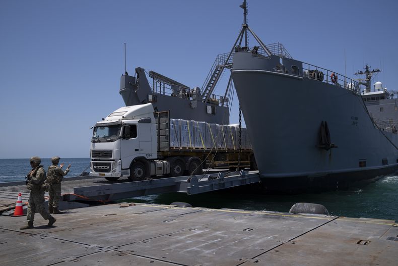 Un soldado del ejército estadounidense da instrucciones a un camión cargado con ayuda humanitaria que desembarca en el muelle flotante construido por Estados Unidos, antes de llegar a la playa, en la costa de la Franja de Gaza, el martes 25 de junio de 2024. (AP Foto/Leo Correa)
