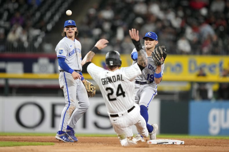 Michael Massey, segunda base de los Reales de Kansas City, lanza a primera después de forzar el out de Yasmani Grandal, de los Medias Blancas de Chicago, en una jugada de doble play, mientras que el parador en corto Bobby Witt Jr. observa durante la quinta entrada del juego de béisbol, el miércoles 13 de septiembre de 2023, en Chicago. (AP Foto/Charles Rex Arbogast)