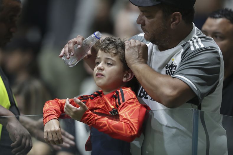 Un hombre vierte agua sobre un niño afectado por los efectos del gas pimienta durante un choque entre policías e hinchas, en el partido de la Copa Libertadores disputado entre Atlético Mineiro y San Lorenzo, el martes 20 de agosto de 2024, en Belo Horizonte, Brasil (AP Foto/Thomas Santos)