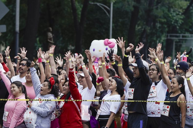 Fans del personaje japonés Hello Kitty saludan antes de una carrera, durante la celebración del 50 aniversario de Kitty, en la Ciudad de México, el domingo 13 de octubre de 2024. (AP Photo/Aurea Del Rosario)