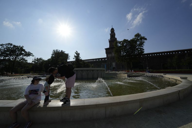 Unos turistas se refrescan en una fuente pública en el castillo Sforzesco en Milán, Italia, el sábado 15 de julio de 2023, en medio de la fuerte ola de calor que azota al sur de Europa. (AP Foto/Luca Bruno)