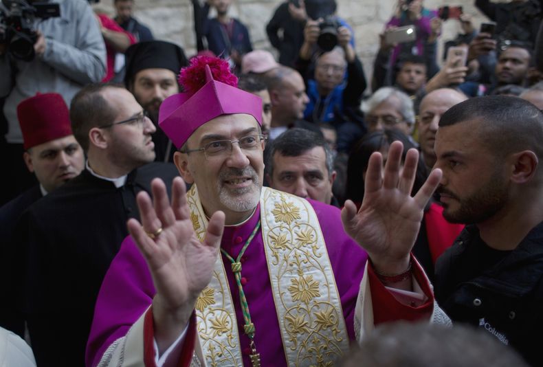 ARCHIVO - En esta imagen, tomada el 24 de diciembre de 2018, cristianos celebran la llegada del arzobispo Pierbattista Pizzaballa, el máximo representante de la Iglesia católica en Tierra Santa, tras cruzar un control militar israelí desde Jerusalén, antes de una misa de medianoche en la Iglesia de la Natividad, reconocida tradicionalmente por los cristianos como el lugar donde nació Jesucristo, en Belén, Cisjordania. (AP Foto/Nasser Nasser, archivo)