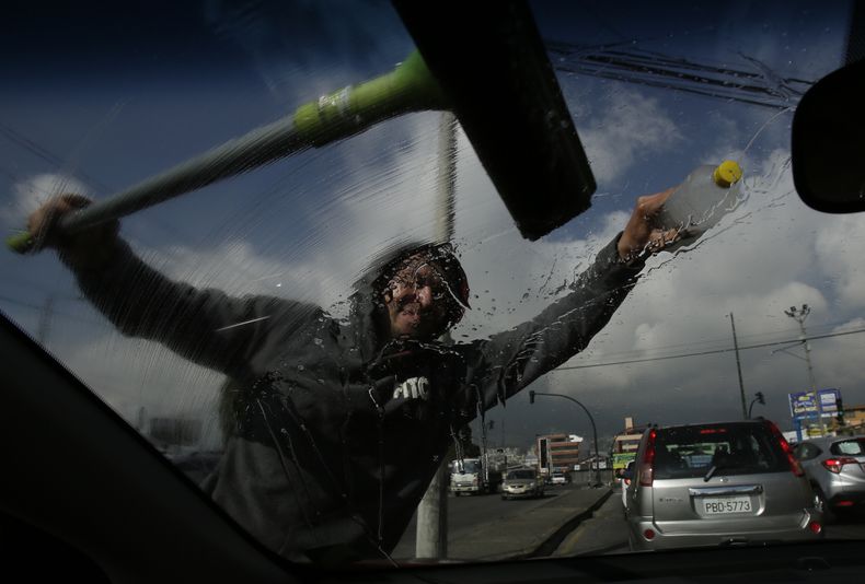 ARCHIVO - Un migrante venezolano limpia un parabrisas en la esquina de una calle en Quito, Ecuador, el 22 de noviembre de 2018. (AP Foto/Dolores Ochoa, Archivo)