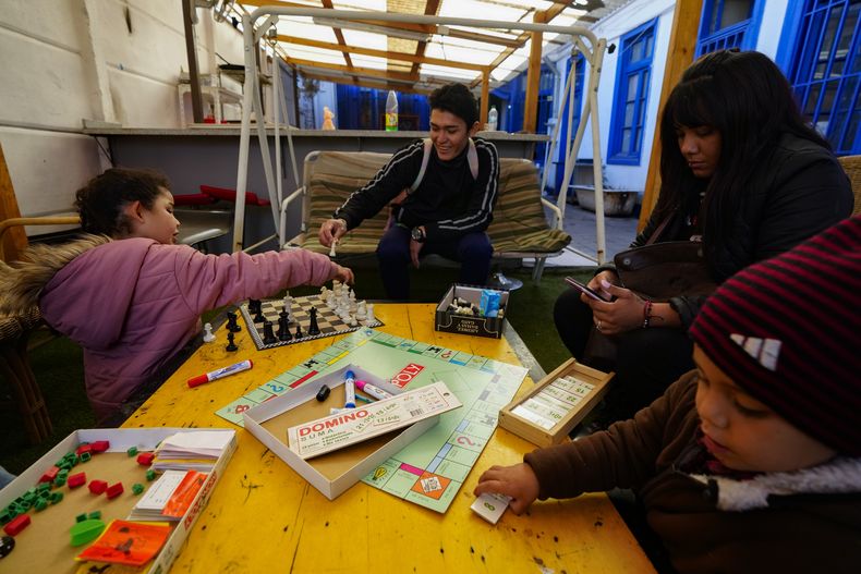 Karen Salazar, segundo por la derecha, y Luis Henrique, en el centro, una pareja de migrantes venezolanos, juegan con sus hijos Malin y Sebastián en el albergue Nuestra Casa en el barrio de Yungay de Santiago, Chile, el jueves 30 de mayo de 2024. Tras salir de Venezuela y encontrarse con una vida como migrantes insoportable en Colombia y luego en Ecuador, la familia se mudó a Chile. (AP Foto/Esteban Félix)