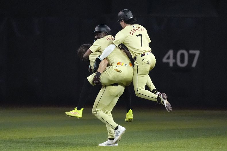 Corbin Carroll y Geraldo Perdomo (centro) festejan con Jake McCarthy, quien conectó el hit del triunfo sobre los Rockies de Colorado, el martes 13 de agosto de 2024 (AP Foto/Ross D. Franklin)