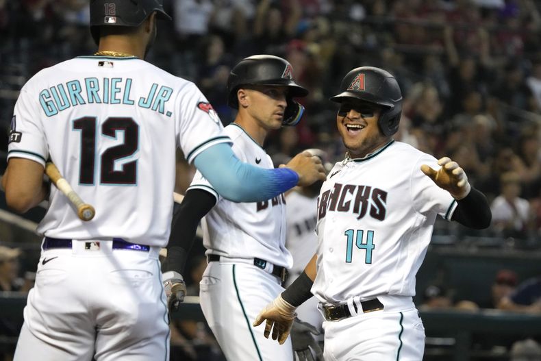 El venezolano Gabriel Moreno de los Diamondbacks de Arizona (14) celebra junto a sus compañeros el cubano Lourdes Gurriel Jr. (12) y Nick Ahmed luego de anotar una carrera impulsada por Jace Peterson en el cuarto episodio del juego ante los Rockies de Colorado en Phoenix. Lunes 4 de septiembre de 2023. (AP Foto/Rick Scuteri)