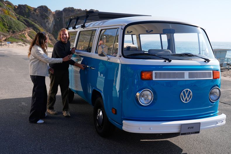 Megan Krystle Weinraub, a la izquierda, y Preston Martin, antiguo propietario, observan su combi Volkswagen el lunes 27 de octubre de 2025 en Malibú, California, después de que VW la restaurara. (AP Foto/Mark J. Terrill)