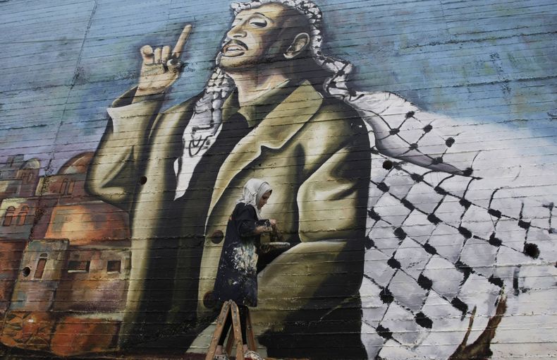 El palestino Hanadi Kharma pinta un mural del fallecido dirigente palestino Yaser Arafat en la ciudad de Naplusa, Cisjordania, el jueves 7 de noviembre de 20213. Un investigador palestino afirma que Israel es el "&uacute;nico sospechoso" en la m