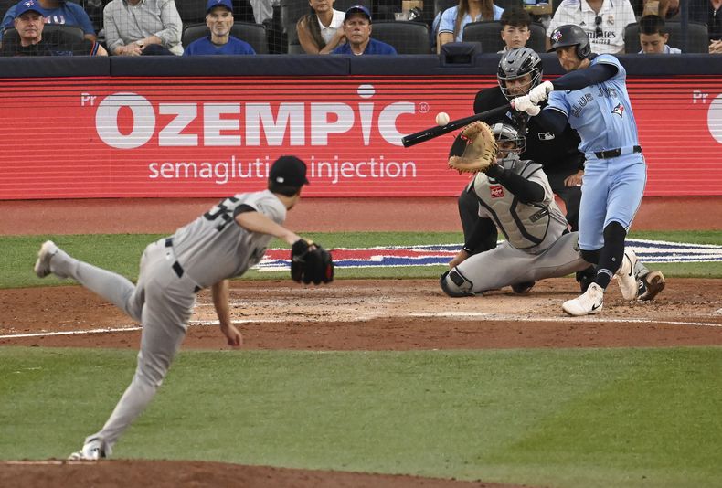 Ernie Clement, derecha, de los Azulejos de Toronto, batea un sencillo frente al abridor de los Yankees de Nueva York Max Fried (54) en la cuarta entrada del juego de béisbol de Grandes Ligas el miércoles 23 de julio de 2025. (Jon Blacker/The Canadian Press vía AP)
