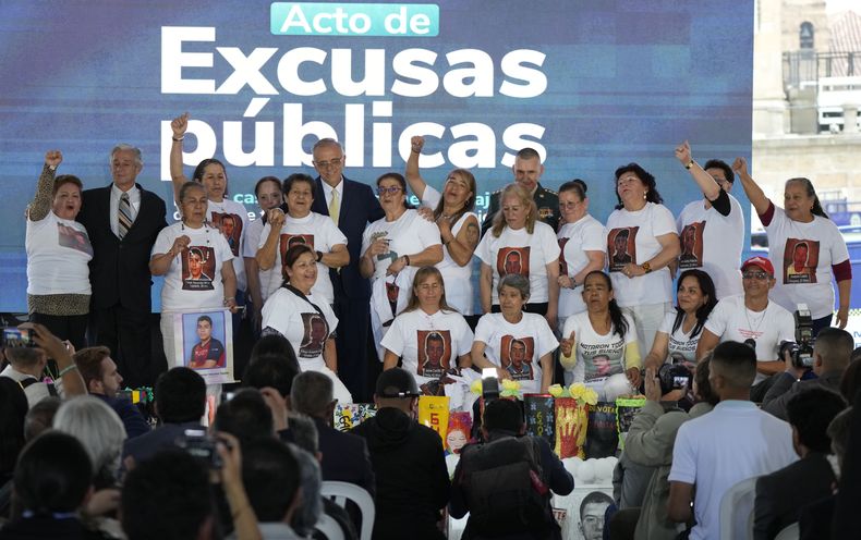 El ministro de Defensa de Colombia, Iván Velásquez, en la fila de atrás, quinto por la izquierda, junto a los familiares de 19 jóvenes que fueron asesinados y presentados falsamente como guerrilleros muertos en combate por el ejército colombiano, en un acto de reconocimiento y disculpas públicas del Estado por las ejecuciones extrajudiciales, en Bogotá, Colombia, el martes 3 de octubre de 2023. (AP Foto/Fernando Vergara)