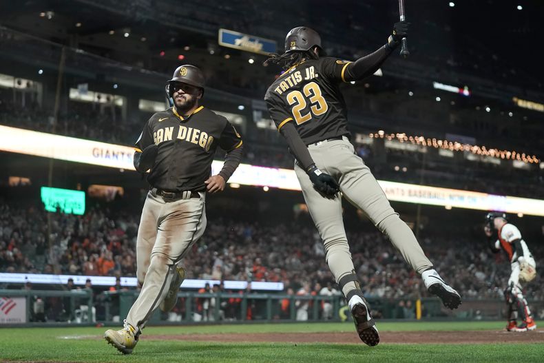 Trent Grisham, de los Padres de San Diego, corre hacia el dominicano Fernando Tatis Jr., luego de anotar ante los Gigantes de San Francisco, el miércoles 27 de septiembre de 2023 (AP Foto/Jeff Chiu)