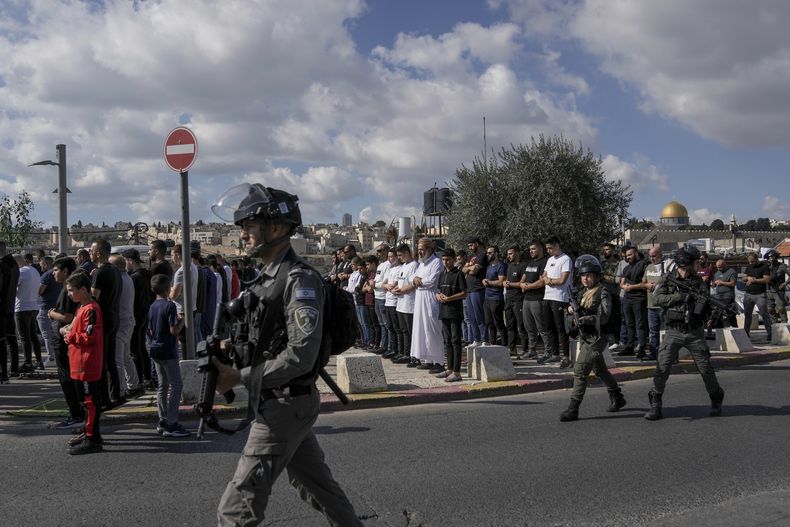 Musulmanes palestinos, a quienes se les prohibió ir a la Mezquita Al-Aqsa en Jerusalén, rezan afuera de la Ciudad Antigua de Jerusalén mientras soldados israelíes montan guardia el 17 de noviembre de 2023.. (Foto AP/Mahmoud Illean)