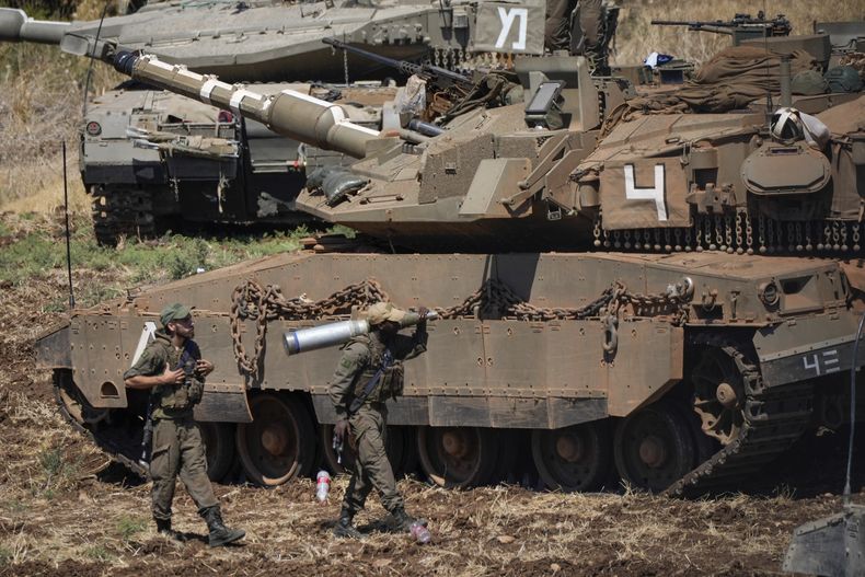 Un soldado israelí carga un proyectil junto a un tanque en el norte de Israel, el 27 de septiembre de 2024. (AP Foto/Baz Ratner)