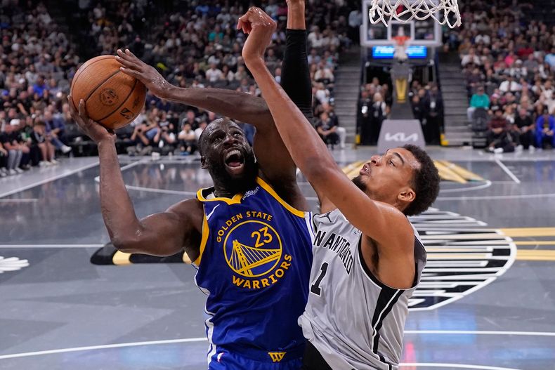 Draymond Green (23), alero de los Warriors de Golden State, conduce al aro contra Victor Wembanyama (1), alero de los Spurs de San Antonio, durante la segunda mitad de un juego de baloncesto de la Copa NBA en San Antonio, el viernes 14 de noviembre de 2025. (AP Photo/Eric Gay)