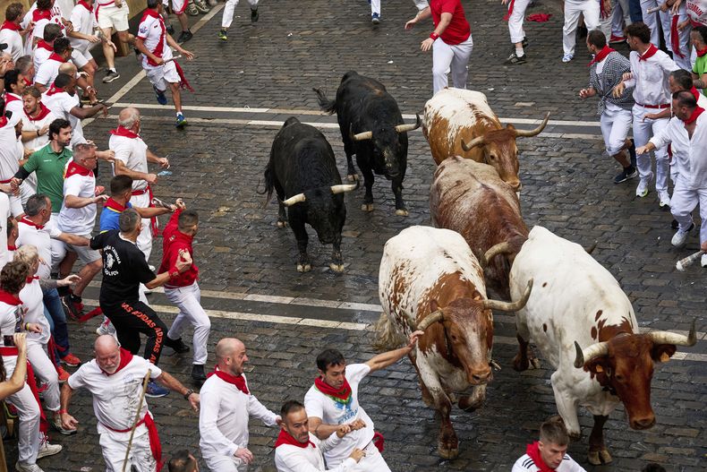 Participantes corren con toros de la ganadería Fuente Ymbro durante el primer día de encierros en las fiestas de San Fermín en Pamplona, España, el lunes 7 de julio de 2025. (AP Foto/Miguel Oses)