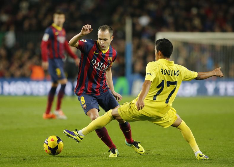 Andr&eacute;s Iniesta, del Barcelona, dribla al mexicano Javier Aquino, del Villarreal, durante un partido de la liga, el s&aacute;bado 14 de diciembre de 2013. El jueves 19 se anunci&oacute; que el Barsa extendi&oacute; hasta 2018 el contrato de Iniesta