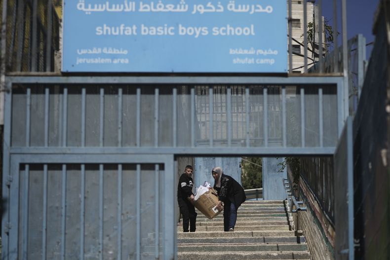 Un estudiante y un maestro sacan materiales de una escuela femenina de UNRWA, gestionada por la agencia de Naciones Unidas para los refugiados palestinos, en el campo de refugiados de Shuafat, en Jerusalén Este, el 8 de mayo de 2025. (AP Foto/Mahmoud Illean)